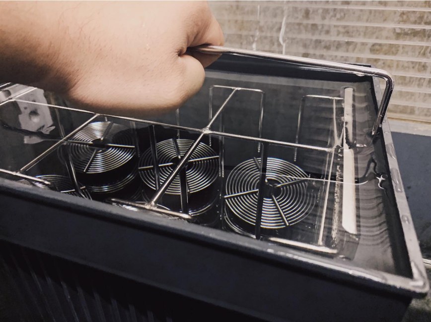 Lifting a basket of loaded film reels out of the black and white dip and dunk tank
